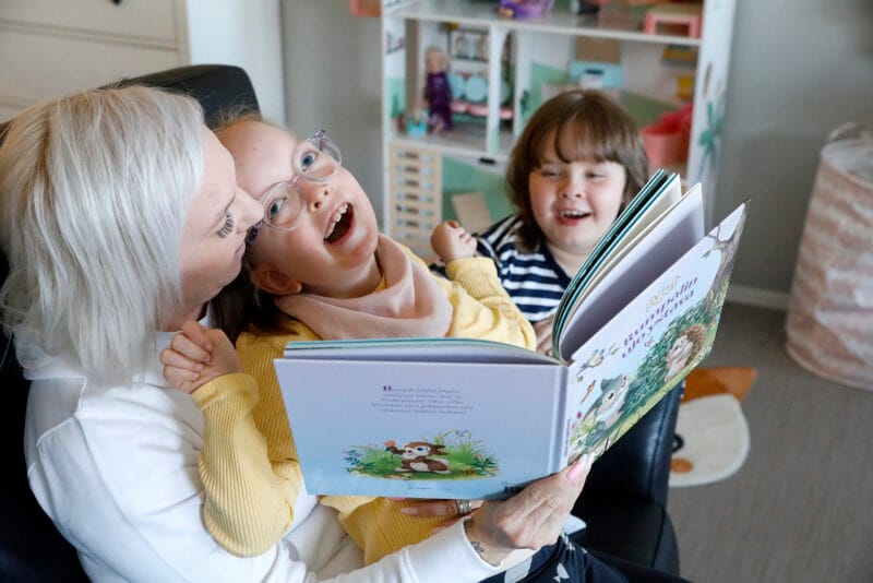 Tärkeintä on kiireetön läsnäolo lasten kanssa. Satukirjaa lukevat Leena Aaltonen, Venla ja Penni.