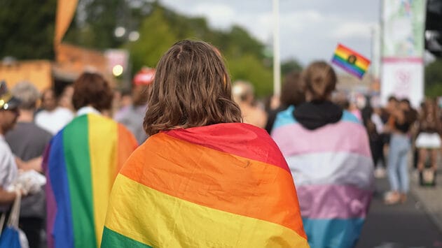 Henkilö kulkueessa pride-lippu harteillaan